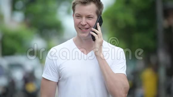 年轻的帅哥在户外的街上使用手机视频的预览图