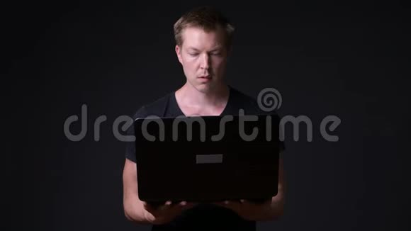 年轻英俊的黑色背景笔记本电脑视频的预览图
