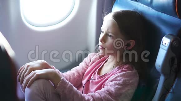 可爱的小女孩乘飞机旅行坐在飞机窗户附近的可爱孩子视频的预览图