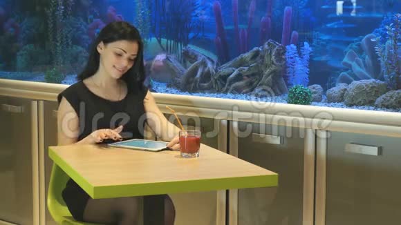 布鲁内特女孩坐在咖啡馆喝果汁视频的预览图