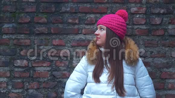 年轻女子微笑着面对砖墙背景视频的预览图