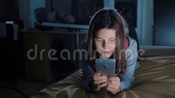 十几岁的女孩网上购物在床上看智能手机一个小女孩写了一篇文章视频的预览图