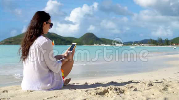 在热带海滩打电话的年轻女子视频的预览图