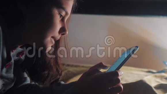 少女和智能手机小青少年帽女孩在社交媒体上留言聊天送信者夜间生活方式视频的预览图