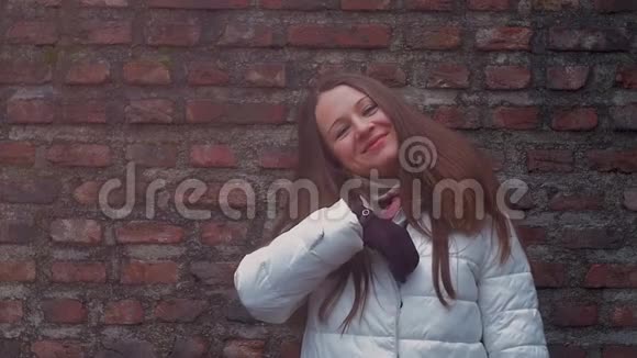 年轻女子微笑着面对砖墙背景视频的预览图