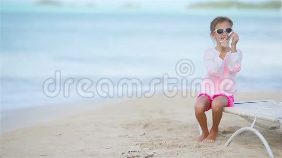快乐的小女孩手里拿着玩具飞机在白色沙滩上视频的预览图