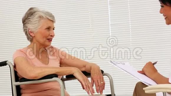 护士与坐轮椅的老年病人交谈视频的预览图