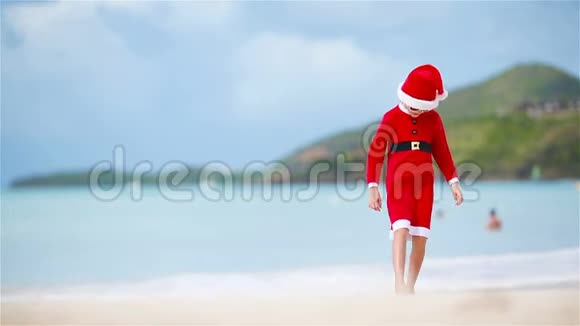 圣诞节假期戴圣诞帽的小女孩在白色海滩上视频的预览图