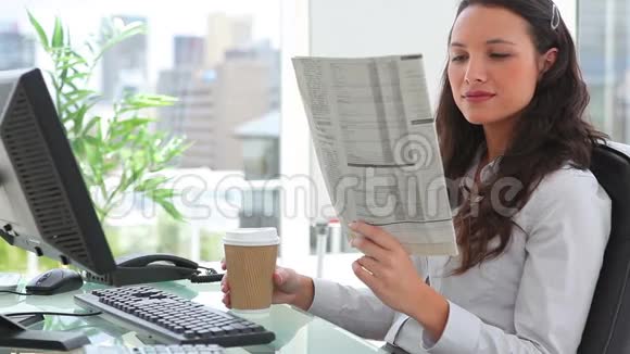 女商人一边喝咖啡一边看报纸视频的预览图