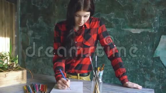 一位年轻的女画家用铅笔在纸笔记本上作画视频的预览图