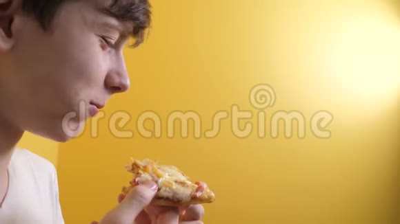 披萨快乐的小男孩吃一片披萨的概念生活方式的十几岁男孩饿了吃一片披萨慢动作视频的预览图