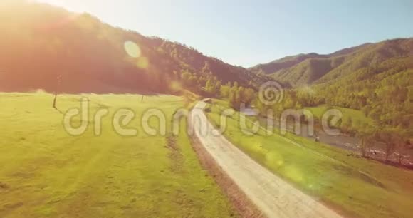 在阳光明媚的夏日早晨中气飞越新鲜的山河和草地农村土路下面视频的预览图