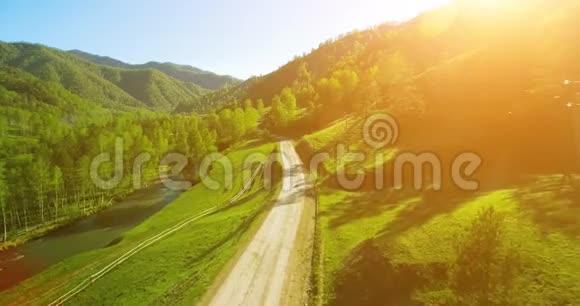 空中UHD4K视野在阳光明媚的夏季早晨低空飞越山区农村土路和草地视频的预览图