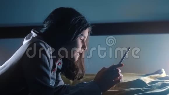 少女生活方式和智能手机一个小少女在社交媒体信使之夜写了一条聊天信息视频的预览图