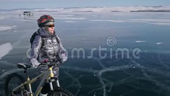 女人在冰上骑着自行车走着女孩穿着银色的羽绒服背包和头盔冰冰视频的预览图