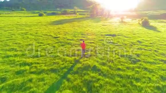 飞越运动男子跑在完美的绿色草地农村草地越野山上日落视频的预览图