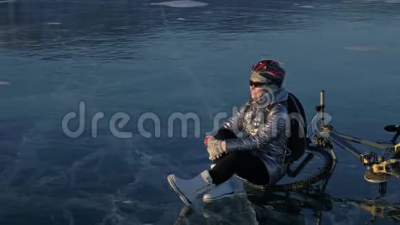 女人在冰上骑自行车女孩穿着银色羽绒服自行车背包和头盔这就是视频的预览图
