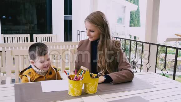母亲和年幼的儿子在餐桌旁画画视频的预览图