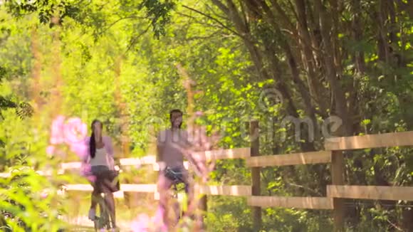 快乐的一对夫妇骑着自行车在夏季公园视频的预览图