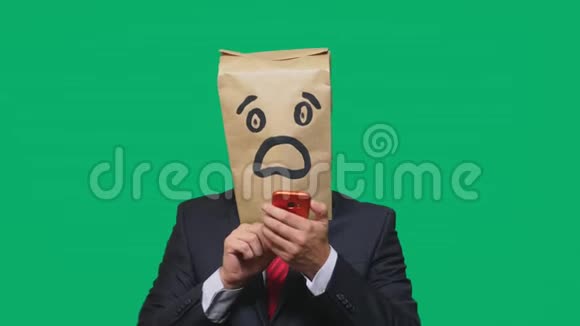 情感概念手势一个头上戴着纸袋的男人带着一种彩绘的表情符号恐惧在手机上聊天视频的预览图