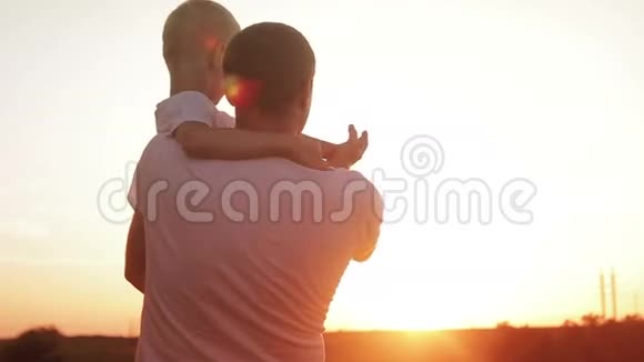 父亲和儿子在田野里享受日落的乐趣视频的预览图