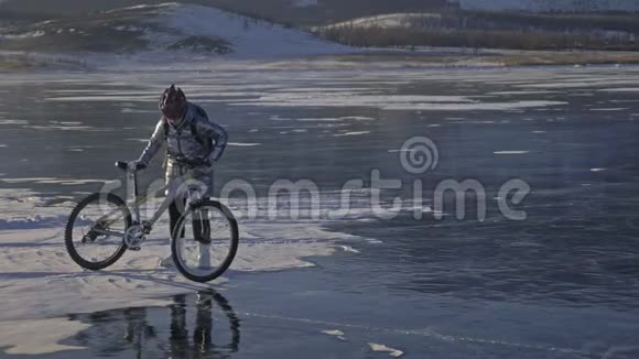 女人在冰上骑自行车女孩穿着银色羽绒服自行车背包和头盔冰冰视频的预览图