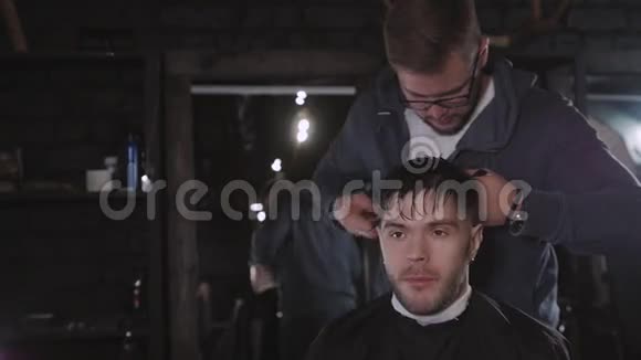 使发型看起来很完美理发店里坐在椅子上时一个留胡子的年轻人正在理发视频的预览图