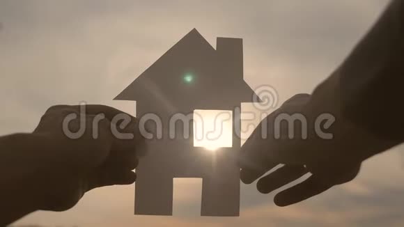 幸福家园建设理念他手里拿着一个纸生活方式的房子手里拿着夕阳的剪影视频的预览图