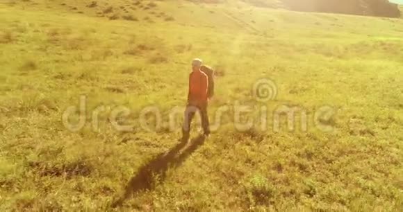 飞行背包徒步旅行游客走过青山野夏日的乡村山谷视频的预览图