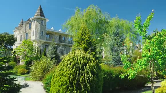 奢华的维多利亚风格酒店沉浸在美丽的树木和灌木丛中屋顶有尖顶背景清澈视频的预览图