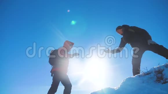 团队合作游客冬季雪商务旅行提供了帮助两个背包徒步旅行的人互相帮助视频的预览图