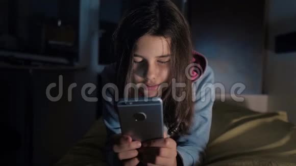 十几岁的女孩网上购物在床上看智能手机一个小女孩写了一条信息视频的预览图