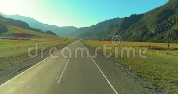 在阳光明媚的夏季早晨低空飞越山路和草地视频的预览图