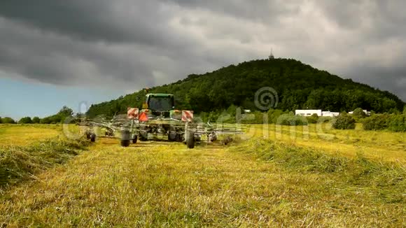 大型收割机正在干草之上转动卡车和干草制造者在农田的草地上工作视频的预览图