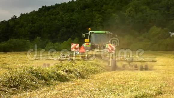 大型收割机正在干草之上转动卡车和干草制造者在农田的草地上工作视频的预览图