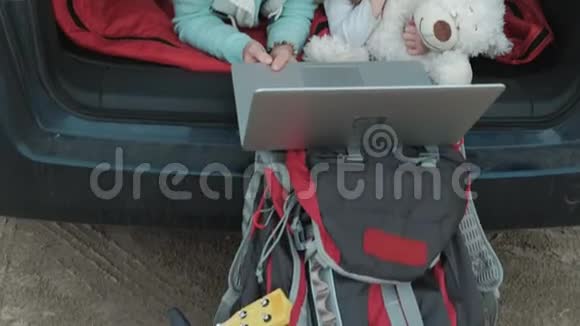 美丽的年轻女子和她的小女儿正坐在海边的一辆敞篷汽车的后备箱里视频的预览图
