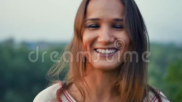 户外一位美丽微笑的年轻女子的肖像慢动作视频的预览图