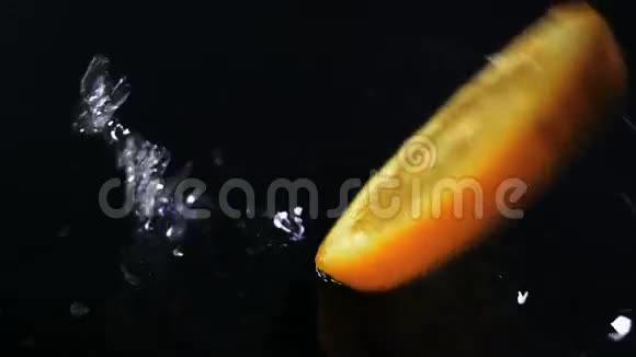 缓慢运动的柠檬在黑色表面上落下水滴视频的预览图