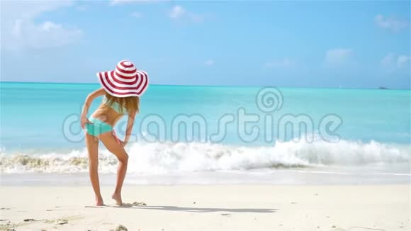 可爱的小女孩戴着大帽子在海滩上视频的预览图