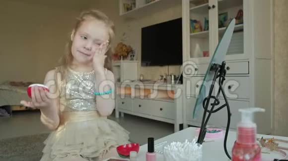 小女孩用红发涂抹乳霜照镜子化妆面部时尚风格化妆品视频的预览图