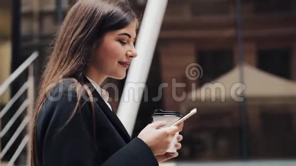 职业年轻女商人用智能手机在城市街道上散步喝咖啡概念新业务视频的预览图