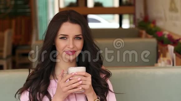 在咖啡馆里喝杯卡布奇诺的女孩视频的预览图