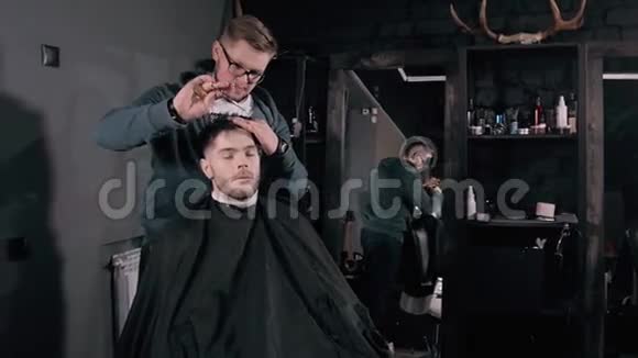 使发型看起来很完美理发店里坐在椅子上时一个留胡子的年轻人正在理发视频的预览图