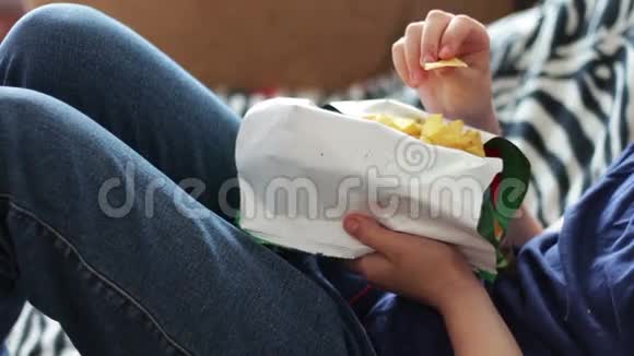 一个十几岁的男孩在家里用手在沙发上吃薯片视频的预览图