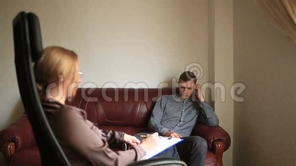 咨询心理学家一位女性治疗师正在咨询一位患有焦虑症的男性患者视频的预览图