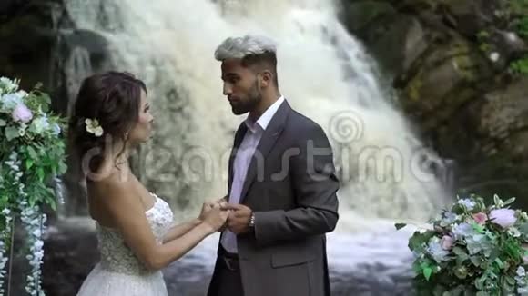 在瀑布附近举行婚礼的新婚夫妇视频的预览图
