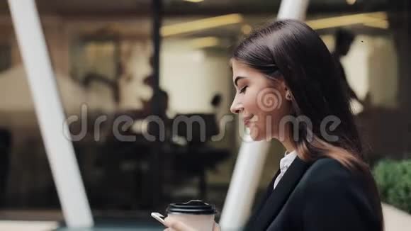 职业年轻女商人用智能手机在城市街道上散步喝咖啡概念新业务视频的预览图