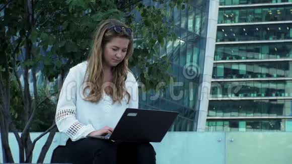 在城市公园用笔记本电脑工作的年轻女商人视频的预览图