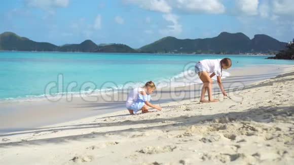 两个快乐的小女孩在热带海滩玩沙玩得很开心视频的预览图