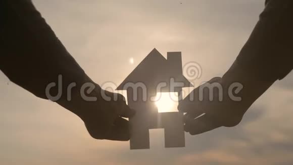 幸福家庭建设住宅理念一个男人手里拿着一个纸房子他的生活方式手里拿着夕阳剪影视频的预览图